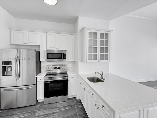 kitchen with sink, light stone counters, dark tile patterned floors, white cabinetry, and stainless steel appliances