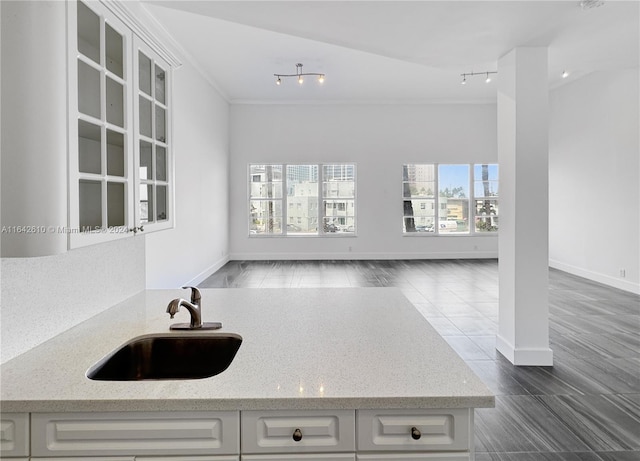 kitchen with rail lighting, sink, and light stone countertops