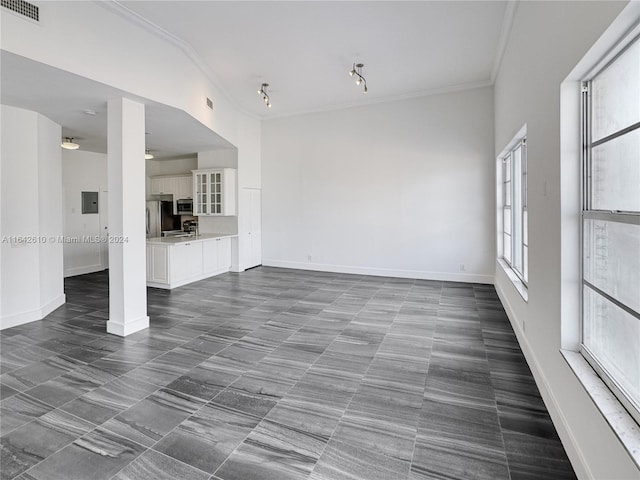 unfurnished living room featuring dark tile patterned floors and ornamental molding