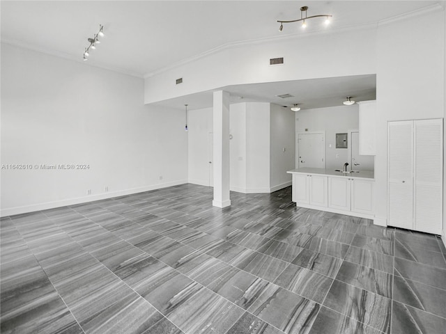 unfurnished living room with rail lighting, sink, ornamental molding, and tile patterned flooring