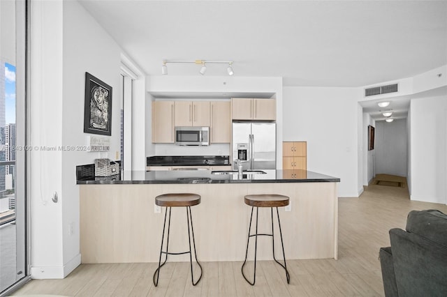 kitchen featuring a breakfast bar, light wood-type flooring, kitchen peninsula, and appliances with stainless steel finishes