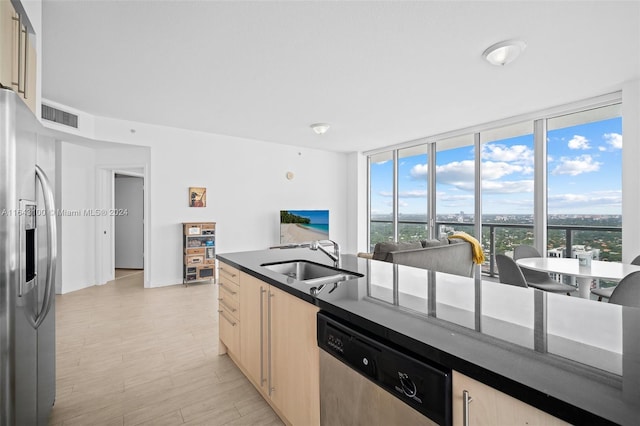 kitchen with appliances with stainless steel finishes, a wall of windows, light brown cabinetry, light hardwood / wood-style flooring, and sink