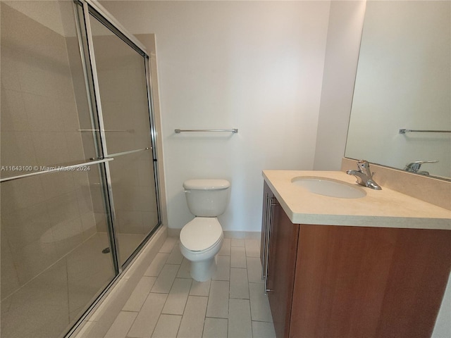 bathroom featuring tile patterned flooring, an enclosed shower, vanity, and toilet