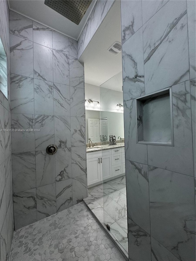 bathroom featuring a tile shower and vanity