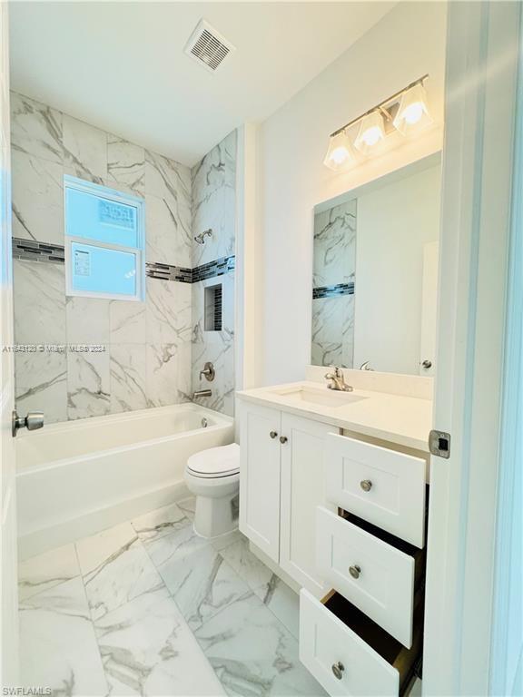 full bathroom with vanity, tiled shower / bath combo, and toilet