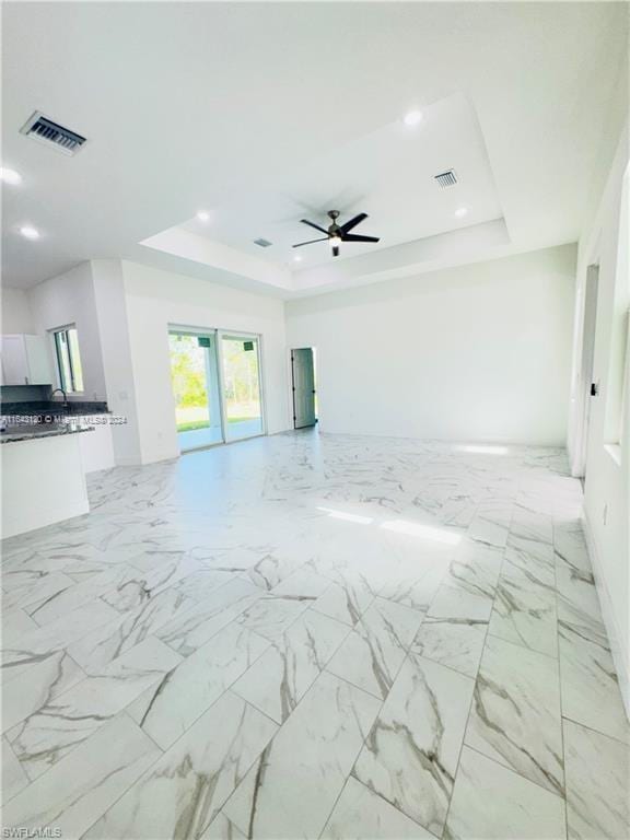 empty room with a raised ceiling and ceiling fan