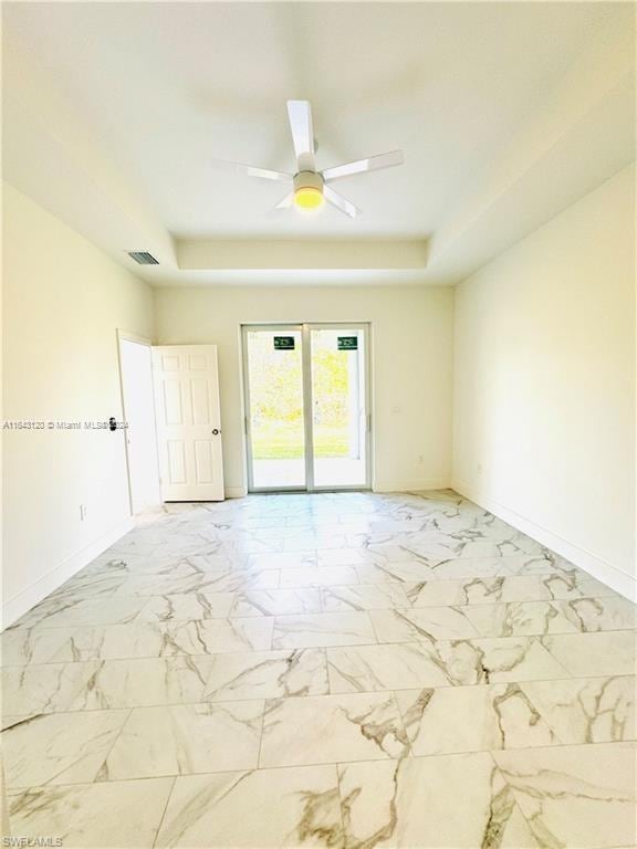 unfurnished room featuring ceiling fan and a raised ceiling