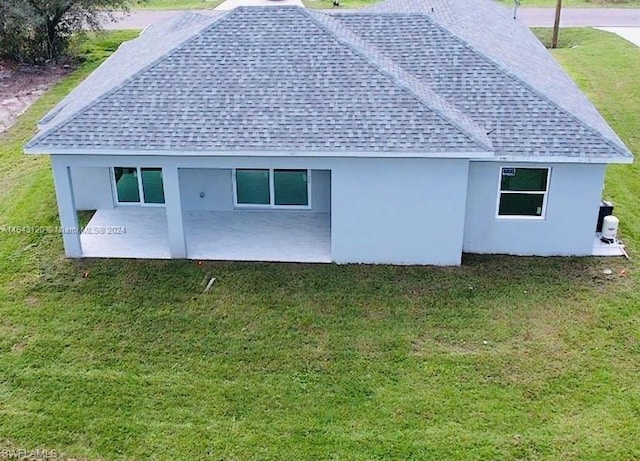 rear view of property featuring a lawn and a patio