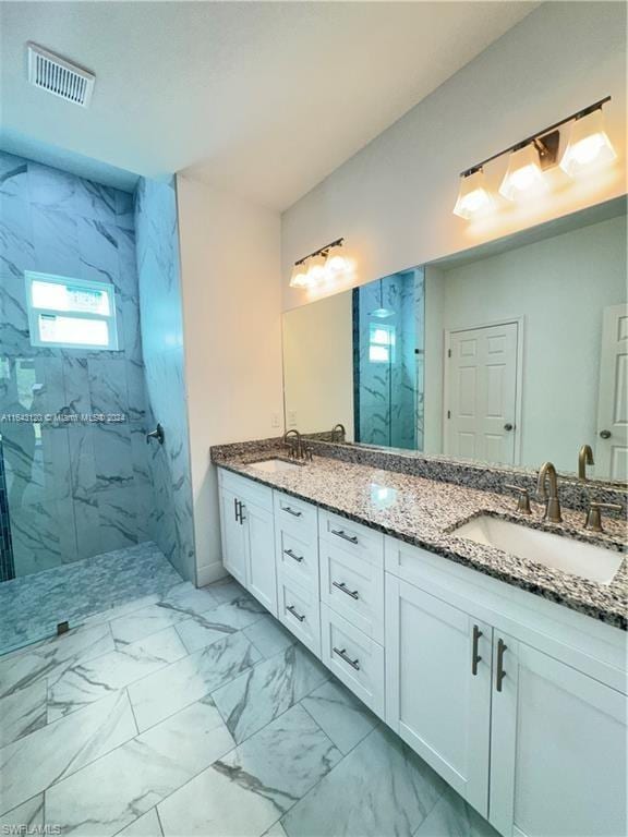 bathroom with a tile shower and vanity