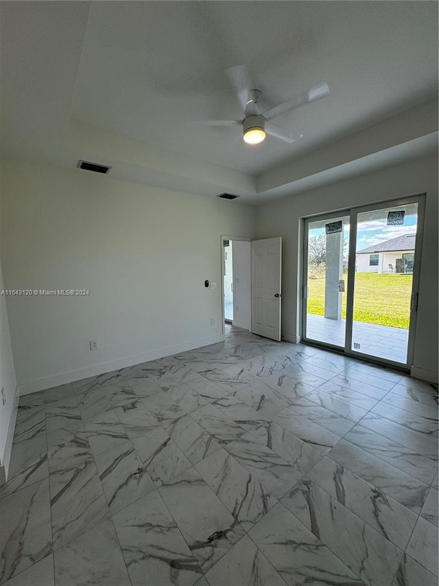 spare room with a raised ceiling and ceiling fan