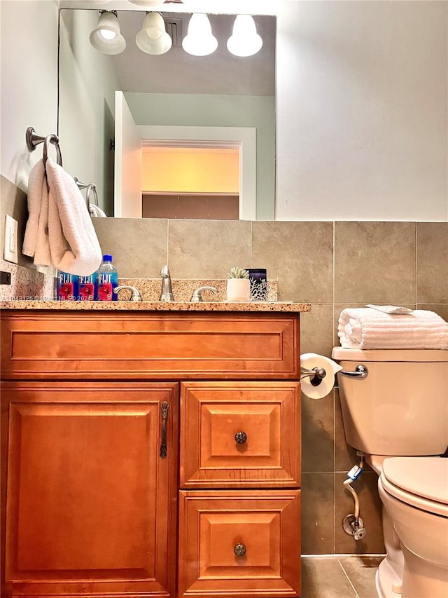 bathroom featuring tile patterned floors, toilet, backsplash, vanity, and tile walls