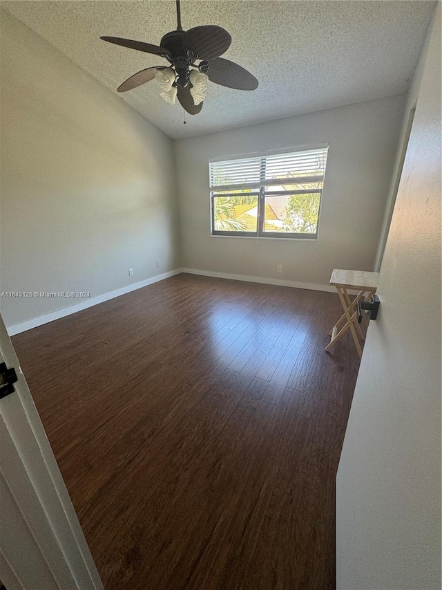 empty room featuring dark wood-type flooring, ceiling fan, and a textured ceiling