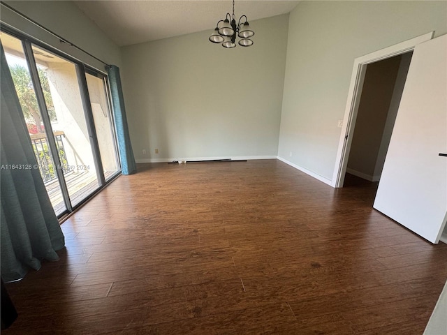 empty room with a notable chandelier and dark hardwood / wood-style floors