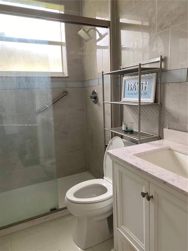 bathroom with tile patterned flooring, vanity, toilet, and a shower with shower door