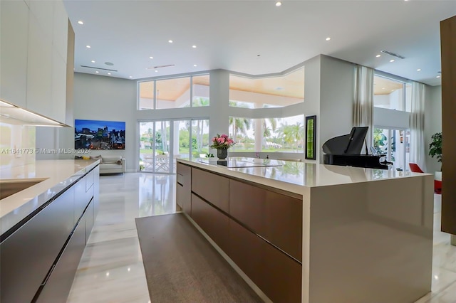 kitchen with black electric cooktop, a spacious island, white cabinets, light countertops, and modern cabinets