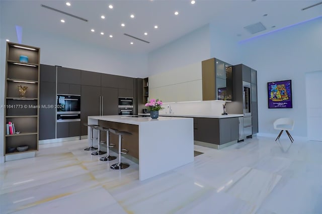 kitchen featuring a breakfast bar area, light countertops, a center island, open shelves, and modern cabinets