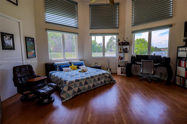 bedroom featuring wood finished floors and a towering ceiling