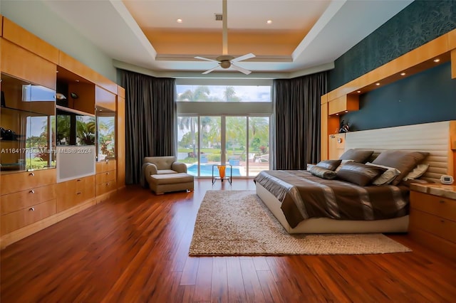 bedroom with dark wood-style floors, a raised ceiling, visible vents, and a high ceiling