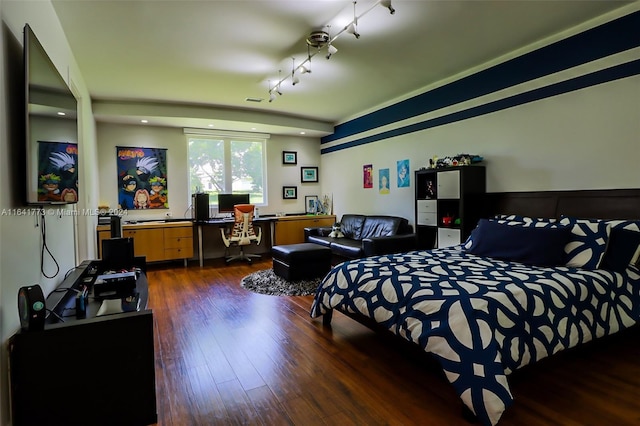 bedroom featuring built in desk, dark wood-style flooring, and track lighting