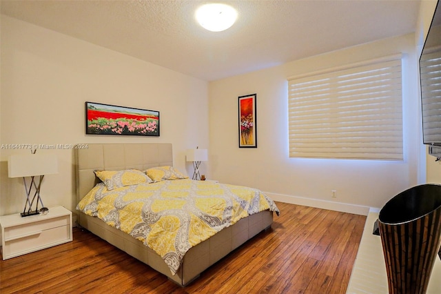 bedroom featuring a textured ceiling, dark wood-style flooring, and baseboards