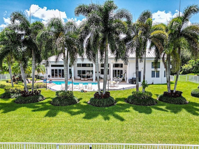 exterior space with an outdoor pool, a patio area, a lawn, and fence