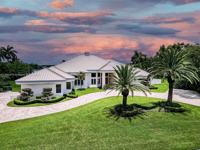 view of front of home with decorative driveway, a standing seam roof, and a front yard