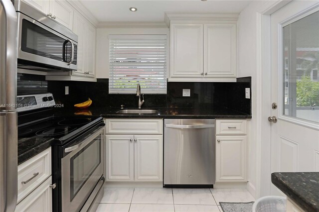 kitchen with appliances with stainless steel finishes, sink, tasteful backsplash, and white cabinets