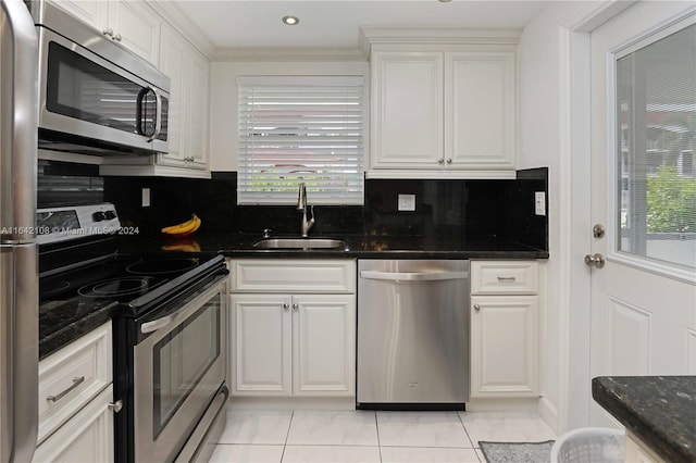 kitchen featuring sink, tasteful backsplash, dark stone countertops, appliances with stainless steel finishes, and white cabinets