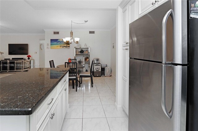 kitchen featuring stainless steel refrigerator, dark stone countertops, ornamental molding, and a kitchen island