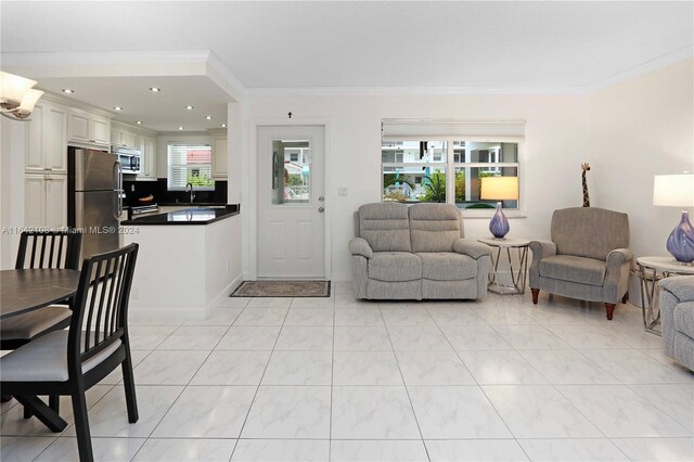 tiled living room with sink and ornamental molding