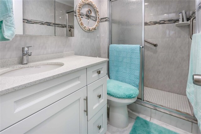 bathroom featuring vanity, tile patterned floors, a shower with shower door, tile walls, and toilet