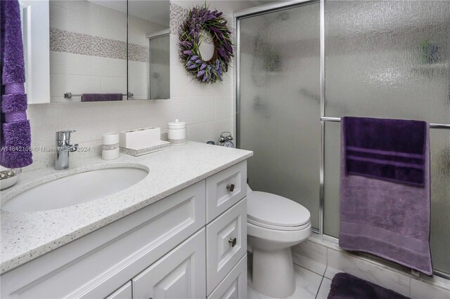 bathroom featuring a shower with door, tile patterned floors, toilet, and vanity