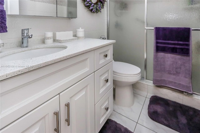 bathroom with tile patterned flooring, a shower with door, toilet, and vanity