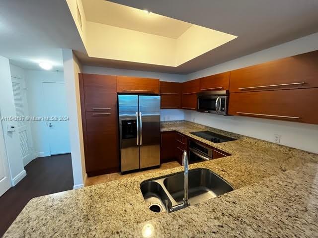 kitchen with appliances with stainless steel finishes, light stone counters, and sink