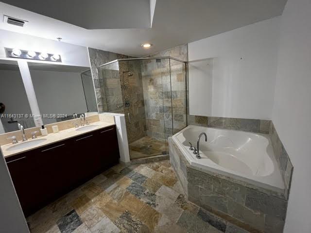 bathroom with independent shower and bath, dual bowl vanity, and tile patterned flooring