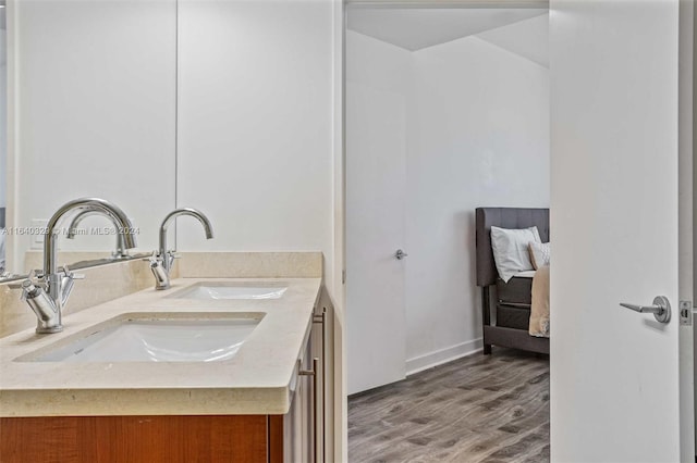 full bathroom with double vanity, baseboards, a sink, and wood finished floors