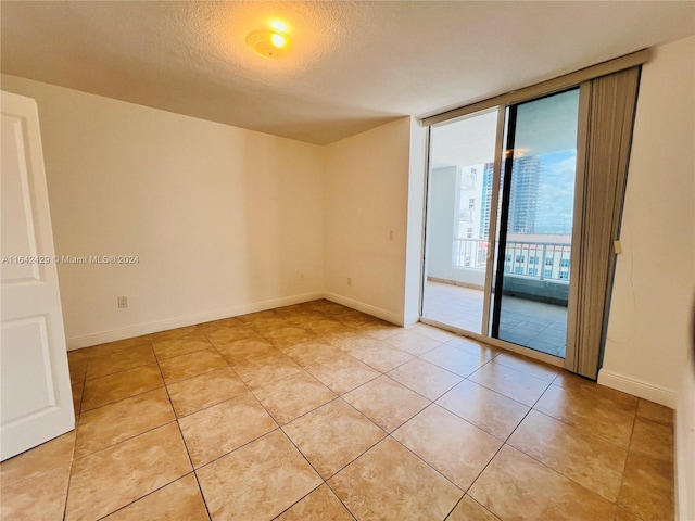 unfurnished room featuring floor to ceiling windows, light tile patterned floors, and a textured ceiling