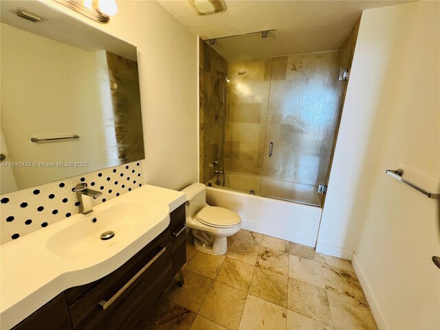 full bathroom with combined bath / shower with glass door, vanity, and toilet