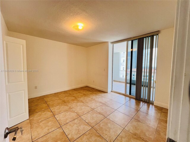 tiled spare room with expansive windows and a textured ceiling