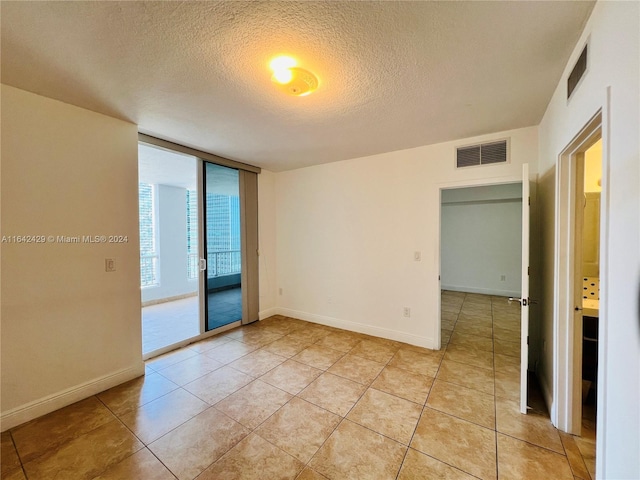 tiled empty room featuring a textured ceiling