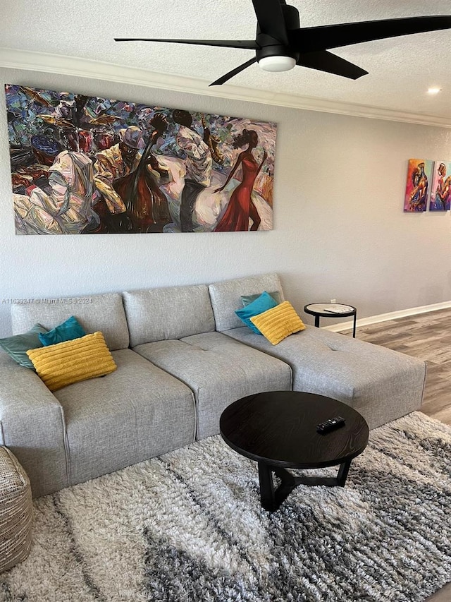 living room with ceiling fan, hardwood / wood-style flooring, ornamental molding, and a textured ceiling