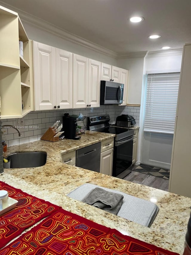 kitchen with sink, appliances with stainless steel finishes, white cabinetry, backsplash, and ornamental molding