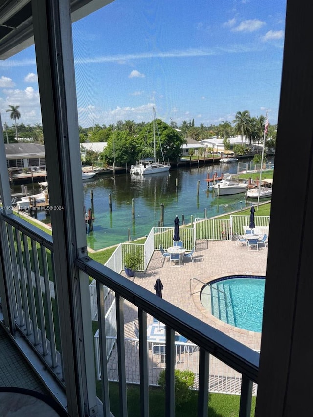 view of pool featuring a water view, a patio, and a dock