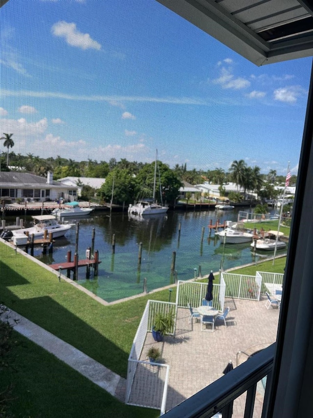 view of dock featuring a balcony, a patio, a water view, and a lawn