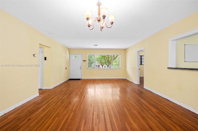 spare room featuring a chandelier and hardwood / wood-style flooring