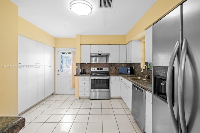 kitchen featuring sink, backsplash, dark stone counters, white cabinets, and appliances with stainless steel finishes