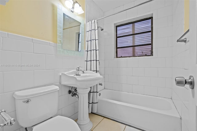 bathroom with tile patterned flooring, toilet, shower / bath combo with shower curtain, and tile walls