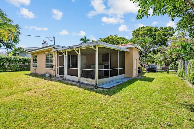 rear view of property with a sunroom and a lawn