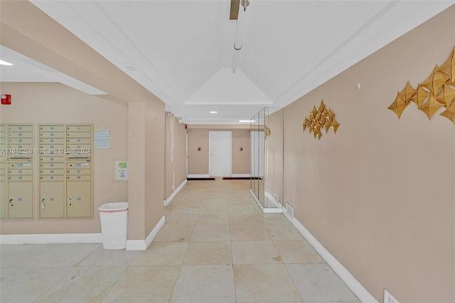 hall with light tile patterned floors, vaulted ceiling, and a mail area