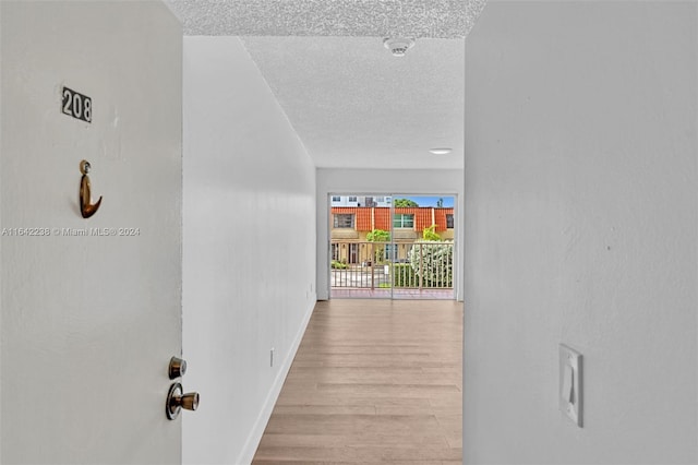 hallway with a textured ceiling and light wood-type flooring